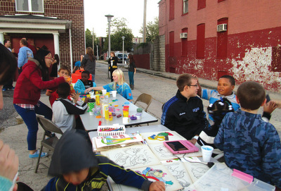 Esther Choi, in red jacket, and Evan Courtney, in black jacket, play with neighborhood children during an outreach event in Baltimore. — EMM
