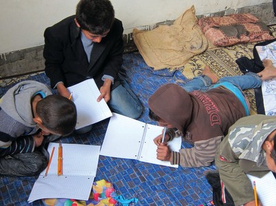 Diab and Amna’s children — from left, Rafi, Odeh, Mahmoud and Ahmed — use supplies from MCC school kits while sitting on an MCC blanket. Diab, Amna and their family of nine boys moved back into their home in December, a livable space that is dry, warm and private. Their home in northern Gaza was selected for repair via a home rehabilitation project funded by MCC through partner Al Najd Development Forum. The family received food and non-food items funded through Canadian Foodgrains Bank, and MCC blankets, school kits and hygiene kits. Only first names are used for security reasons. —  Jesse Bergen/MCC