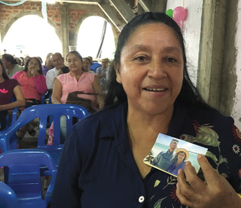 Maria holds a photo of Rick and Carole Skinner, members of Hyde Park Mennonite Fellowship, that she has carried in her Bible since 2011 as a reminder of Hyde Park’s prayers for her. She prays for the Skinners daily. — Rob Hanson