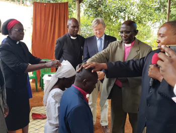 Mennonite World Conference vice president Rebecca Osiro, left, and Kenya Mennonite Church bishop Dominic Opondo and bishop Sungura Garant of Canada, right, lay hands on Okoth Simon Onyango and his wife, Alice Onyango, at an Aug. 11 worship service in Mukono, Uganda, making Onyango Uganda Mennonite Church’s first bishop. Francis Ojwang of Kenya, second from left, and MWC President Henk Stenvers of the Netherlands look on. — Mennonite Church Uganda