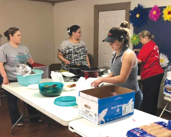 Women from New Life Christian Center serve Stone Soup Ministry to-go plates in March for community members needing meals. — Maria Hinojosa
