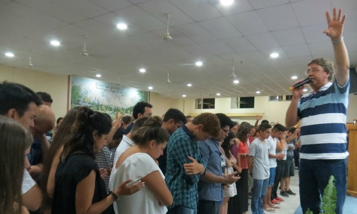 Photo: ​Pastor Daniel Oyanguren prays for youth and young adults who came forward in response to a missionary call at the January assembly of the Iglesia Evangélica Menonita Argentina (IEMA) in Choele Choel. The IEMA sends missionary church planters throughout the country. Photo by Linda Shelly.